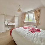Bright bedroom with floral decor and dressing table.