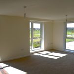Bright empty room with large windows and carpeted floor.