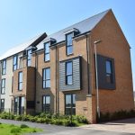Modern three-storey brick building under clear blue sky.