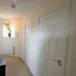 Bright hallway with light fixture and doors.