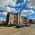 Residential street with modern flats under blue sky.