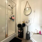 Modern bathroom with shower, mirror, and sink.