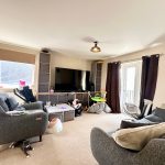 Spacious living room with grey sofas and large TV.