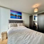 Modern bedroom with city view artwork above bed.