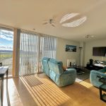 Bright living room with sofas and TV, sunny view.