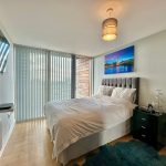Modern bedroom with TV, artwork, and large windows.