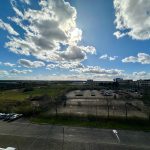 Sunny day over empty car park and green fields.