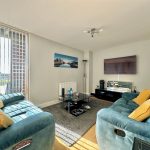 Modern living room with teal sofas and wall art.