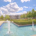 Modern courtyard with fountains and hedges.