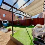 Sunny patio with seating, grass, and garden shed.