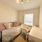 Small bedroom with daybed, wicker chair, and desk.