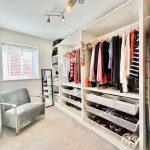 Organised walk-in wardrobe with hanging clothes.