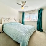 Bright bedroom with teal curtains and bedspread.