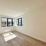 Bright empty room with large windows and wooden flooring.