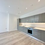 Modern kitchen with grey cabinets and wooden flooring.