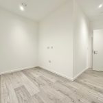 Empty room with wooden flooring and white walls.