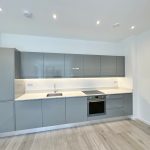Modern kitchen with grey cabinets and wooden floor.