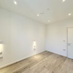 Minimalist empty room with wooden floor and spotlights.