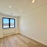 Empty room with wooden floor and large window.