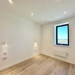 Empty, modern room with wooden floor and large window.