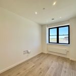 Empty room with large window and wooden floor.