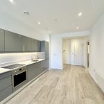 Modern kitchen with grey cabinets and wooden flooring.