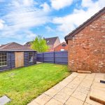 Brick house with garden and wooden shed in backyard.