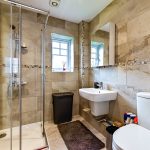 Modern bathroom with shower, sink, and toilet.