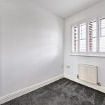 Empty room with carpet and shuttered window.