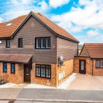 Modern brick house with red roof and blue sky.