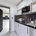 Modern kitchen with black tiled backsplash and appliances.