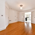 Spacious room with wooden floor and double doors.
