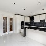 Modern kitchen with white cabinets and black counters.