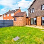 Backyard of a brick house with fence and lawn.