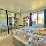 Spacious bedroom with mirrored wardrobe and large window.