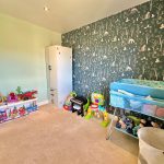 Colourful children's nursery with toys and forest wallpaper.