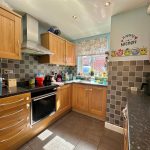Modern kitchen with wooden cabinets and tiled backsplash.