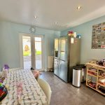Bright kitchen with table, fridge, and storage shelves.