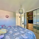 Cosy bedroom with mirrored wardrobes and patterned bedding.