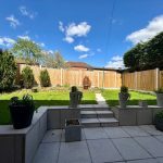 Sunny garden with lawn and potted plants.