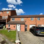 Brick terraced house with cars on driveway.
