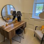 Modern home office with desk, mirror, and chair.
