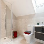 Modern bathroom with shower, toilet, and skylight window.