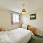 Bright bedroom with double bed and window view.