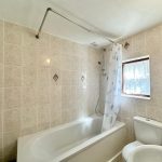 Tiled bathroom with bathtub and shower.