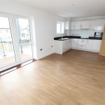 Modern kitchen with wooden floor and balcony doors.