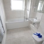 Modern bathroom with bathtub, sink, and tiled floor.