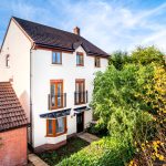 Modern three-storey house with garden in autumn.