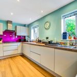 Modern kitchen with light cabinets and green walls.