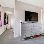 Bedroom with grey dresser and large TV